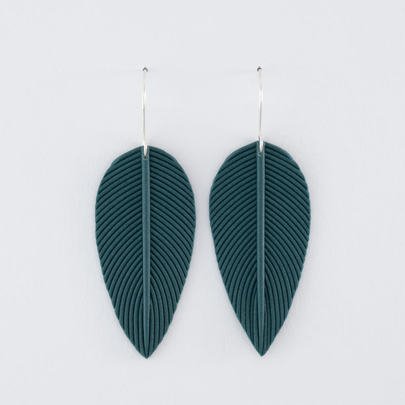 Folium N°1 handmade dangle earrings – delicate, leaf-shaped statement earrings in smokey teal, fitted with 925 sterling silver findings on a light grey background.