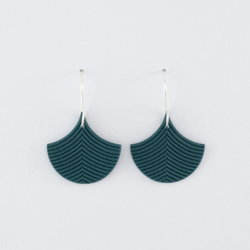 Folium N°3 handmade dangle earrings – delicate, ginkgo leaf-shaped earrings in smokey teal, fitted with 925 sterling silver findings on a light grey background.