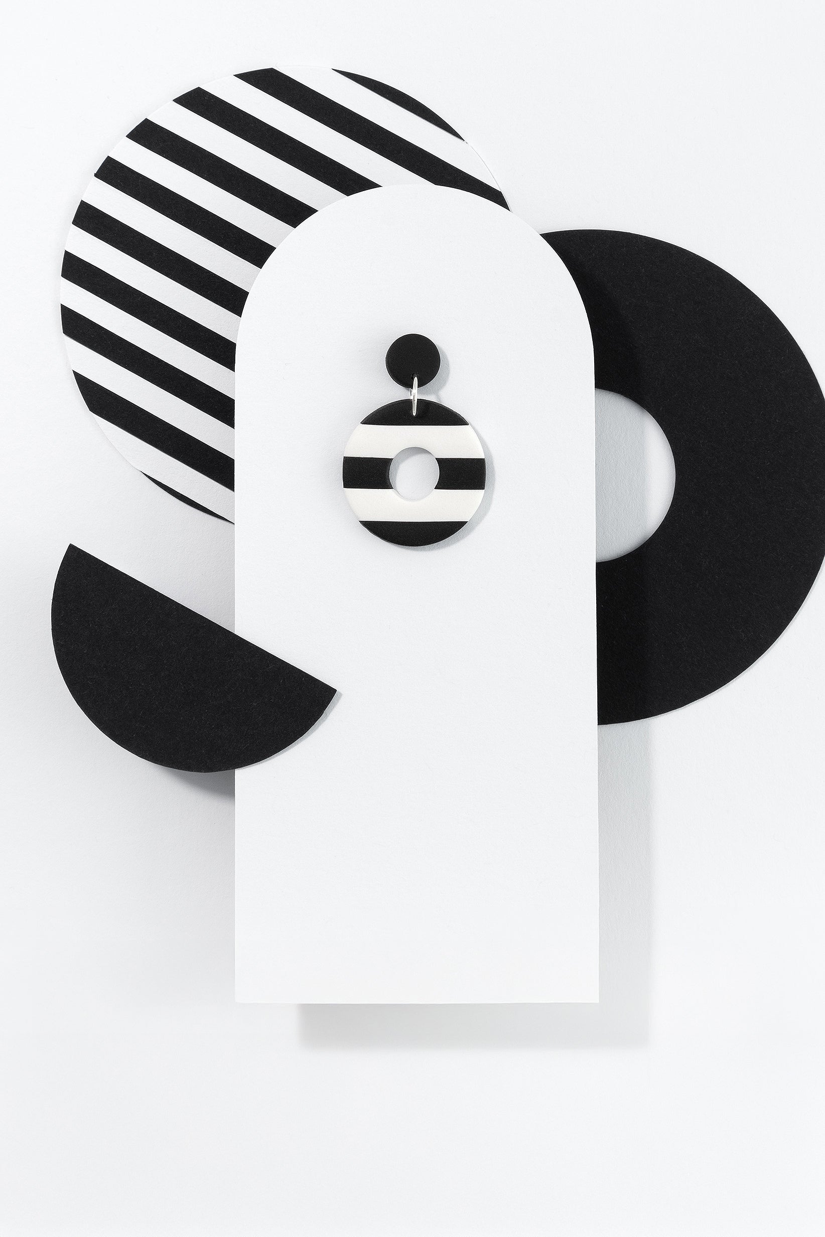 Black & White N°1 handmade dangle earring with 925 sterling silver findings from Portamira’s Black & White collection – round, black and white striped earring on geometric display.