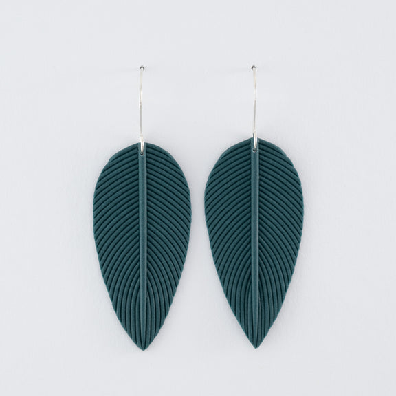 Folium N°1 handmade dangle earrings – delicate, leaf-shaped statement earrings in smokey teal, fitted with 925 sterling silver findings on a light grey background.