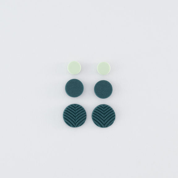 A set (3 pairs) of Folium N°5 handmade studs – delicate, round, nature-inspired earrings in smokey teal and pale green with 925 sterling silver findings on a light grey background.