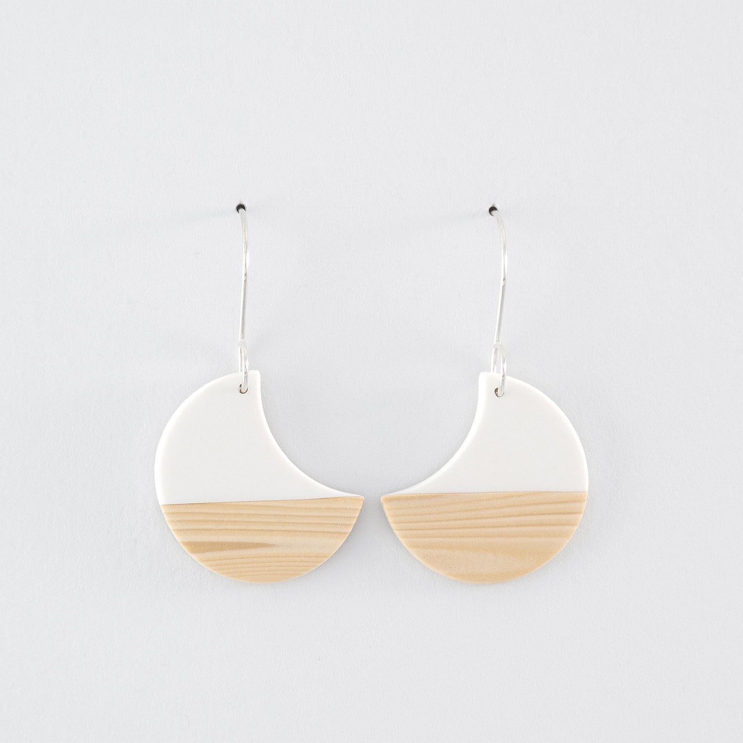 Kyoto N°2 handmade dangle earrings – mirrored, white sailboat- or crescent-shapes with woodgrain pattern and 925 sterling silver findings on light grey background.